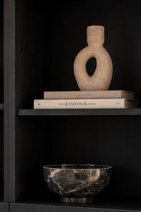 Stylingdetail: vaas en boeken op een plank in de kast